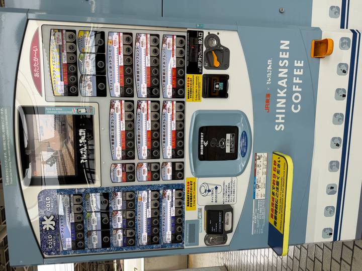Front view of a Japanese vending machine themed around Shinkansen coffee options.