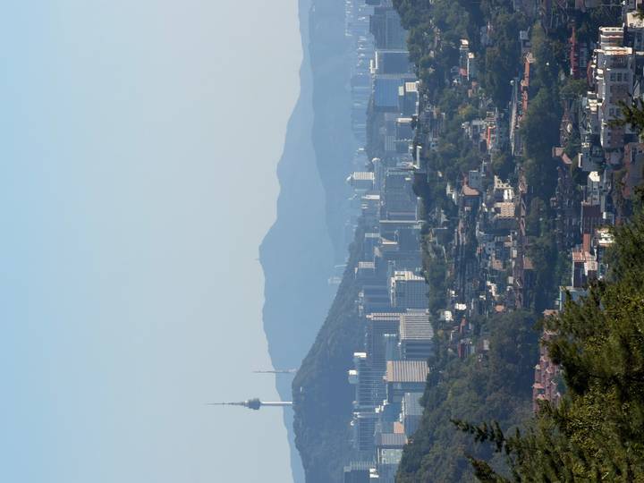 Wide Seoul cityscape with mountains and Namsan Tower visible under clear sky.