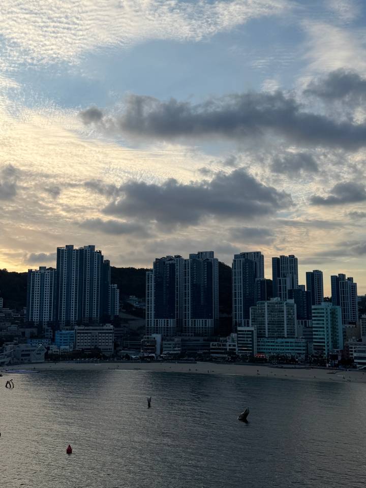 Modern high-rise towers silhouette against dramatic evening clouds above the city.