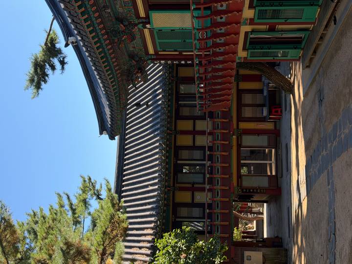 Quiet temple courtyard with colourful wooden balconies and tiled roofs in soft light.