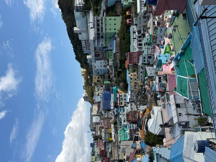 Colorful hillside neighborhood with stacked houses beneath a bright blue sky.