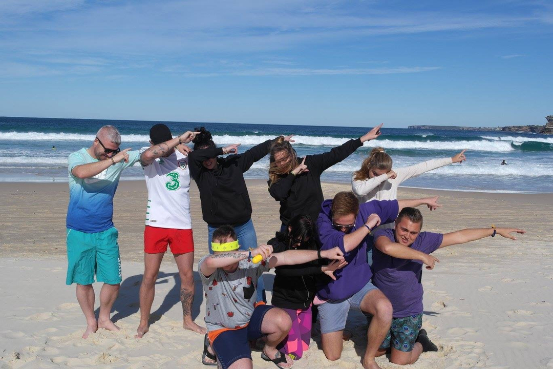 A group of people doing a dance pose on a beach.