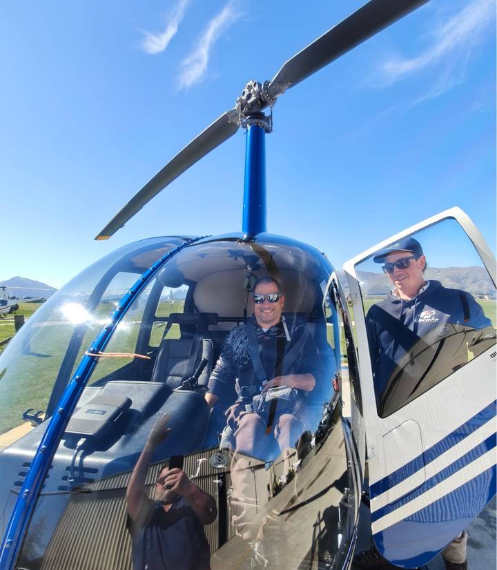 Traveller seated in a helicopter cockpit prepares for scenic flight with pilot beside.