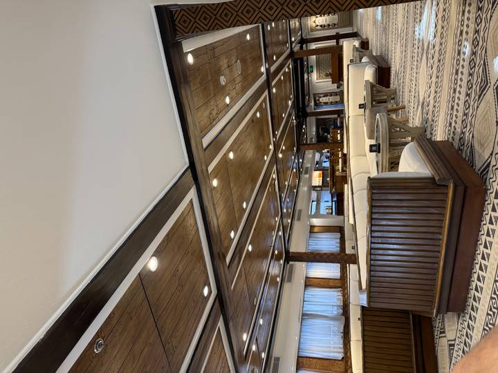 Elegant lounge area on a river cruise ship with wooden ceiling panels, patterned carpet and cushioned seating