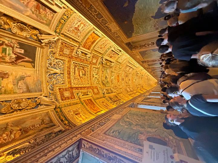 Crowds walk beneath the ornately frescoed golden ceiling of the Vatican’s Gallery of Maps.
