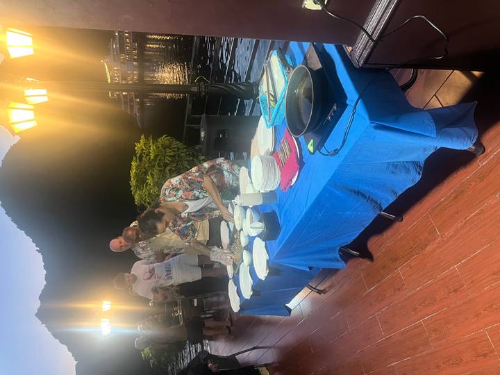 Chef demonstrating spring-roll making on a cruise deck at night with guests watching.