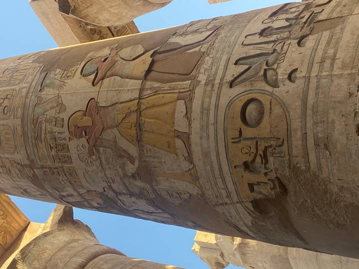 Close-up of richly colored hieroglyphic reliefs depicting pharaohs and deities on a massive temple column.