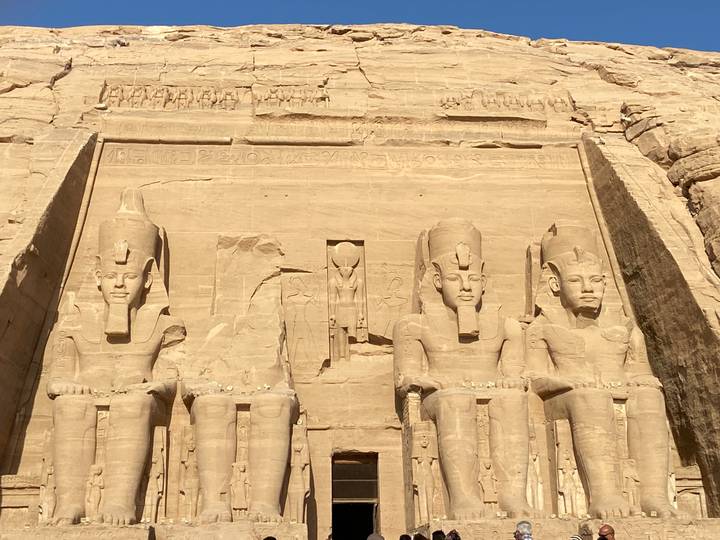 Impressive rock-cut statues of Ramesses II at Abu Simbel Temple bathed in warm sunlight.