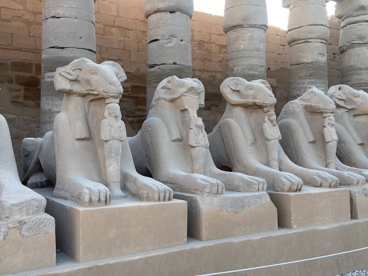 Row of sandstone ram-headed sphinx statues lining the avenue at Karnak Temple.