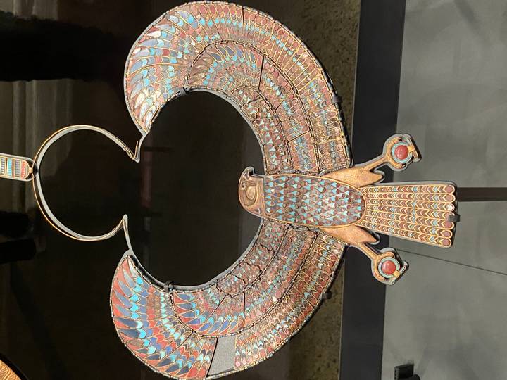 Exquisitely crafted ancient Egyptian pectoral jewelry in the form of a falcon displayed in a museum case.