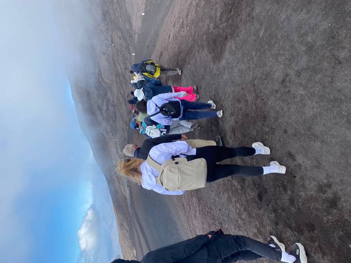 Tour group hikes along volcanic ash slopes in the mist on Mount Etna.