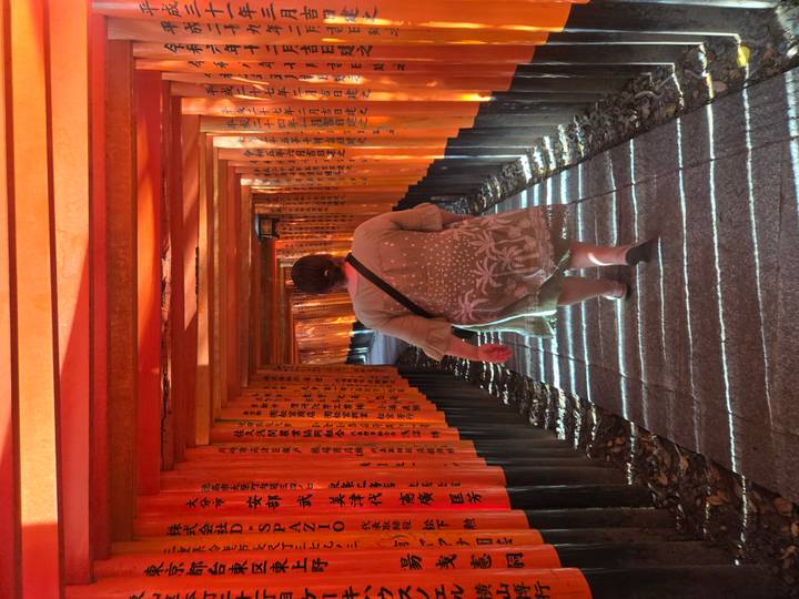 A visitor walks through an endless tunnel of bright orange torii gates at Kyoto’s Fushimi Inari Shrine.