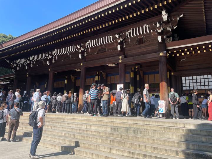 Long queue of visitors waiting to enter a historic wooden shrine in Tokyo.