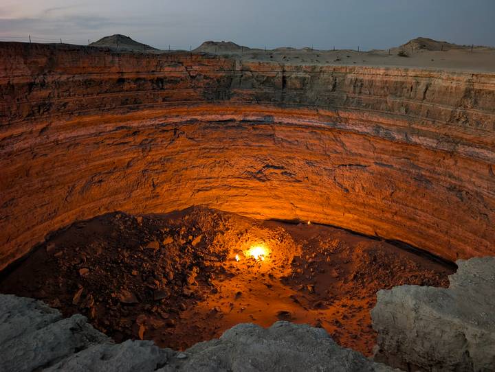 Fiery glow illuminating the base of a vast desert crater at night.