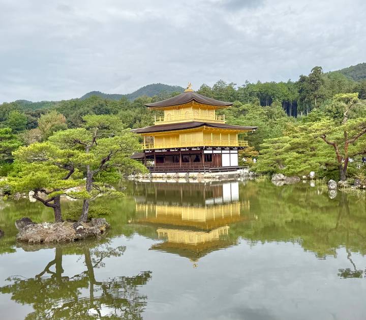 Golden Pavilion (Kinkaku-ji) reflected perfectly in a tranquil pond surrounded by greenery.