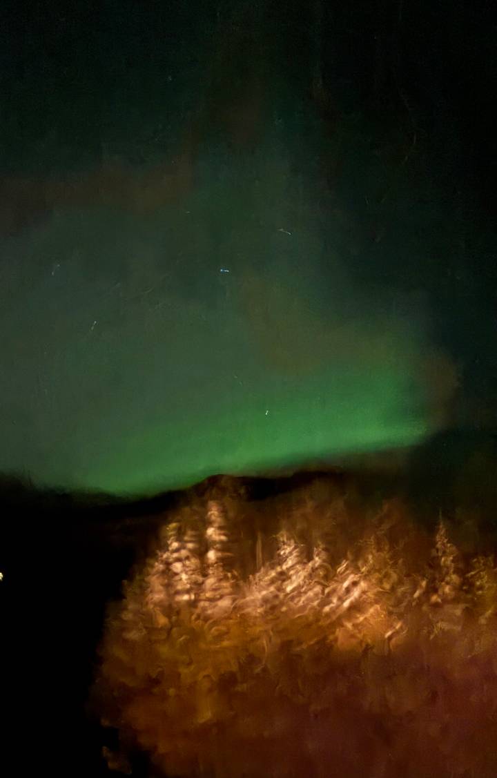 Dark night sky with a green aurora borealis glow above a faint horizon.