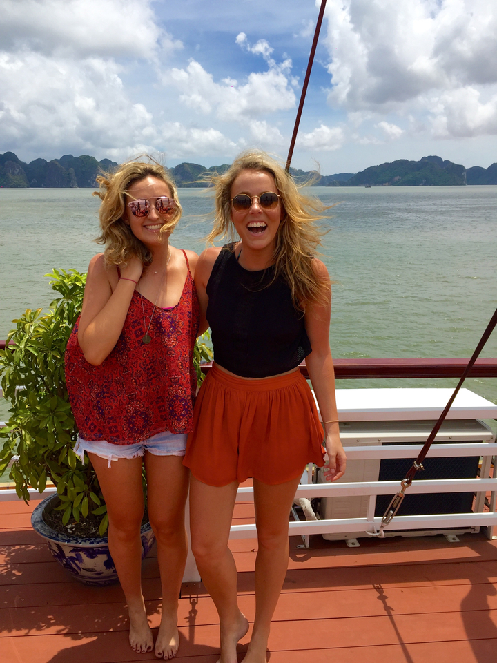 Two women smiling on a boat with ocean view.