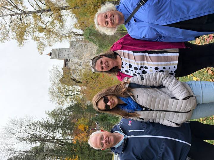 Travelers posing with autumn foliage and a medieval hilltop castle in the background.