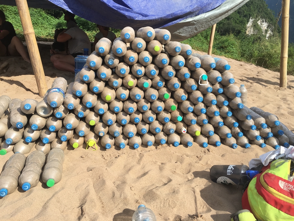 Pyramid made of plastic bottles on a sandy surface.