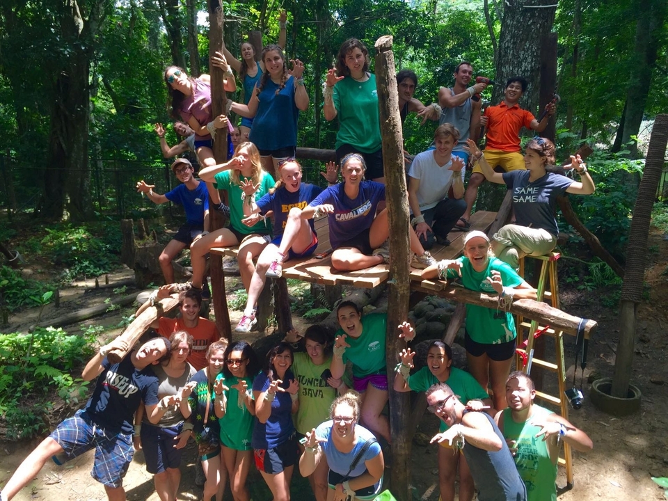 Group of people on a playground made of logs in a forest.