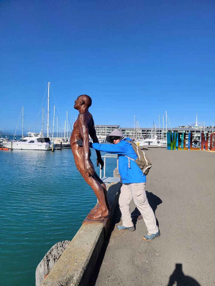 Une image pivotée montrant une personne et une statue près de l'eau.