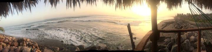 Sunset view of the ocean with the silhouette of a roof.
