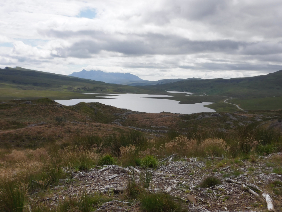 A lake surrounded by hills and an overcast sky.