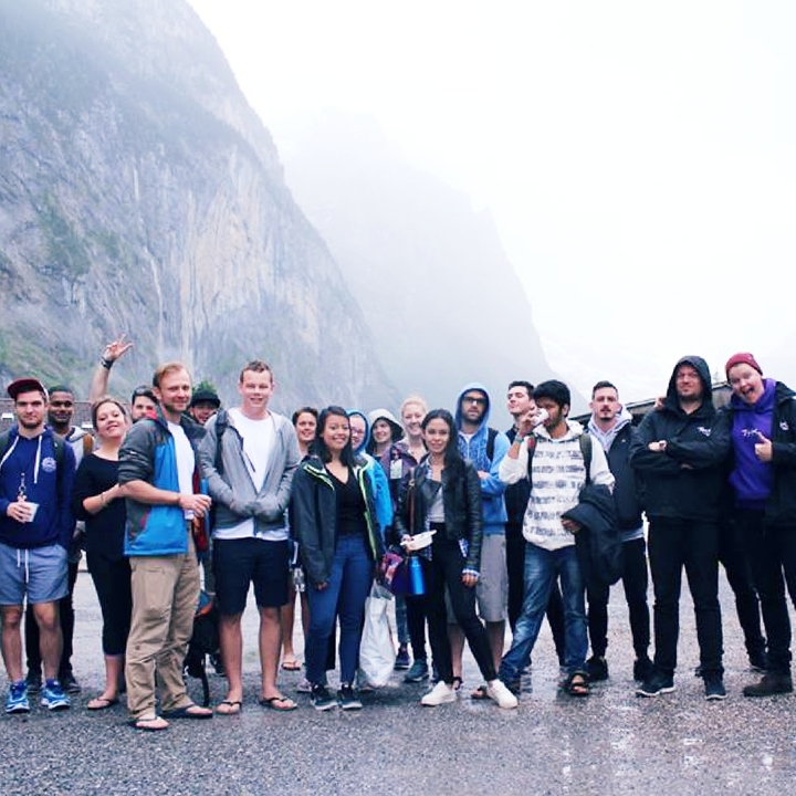 A large group of tourists posing for a photo with mountains in the background.