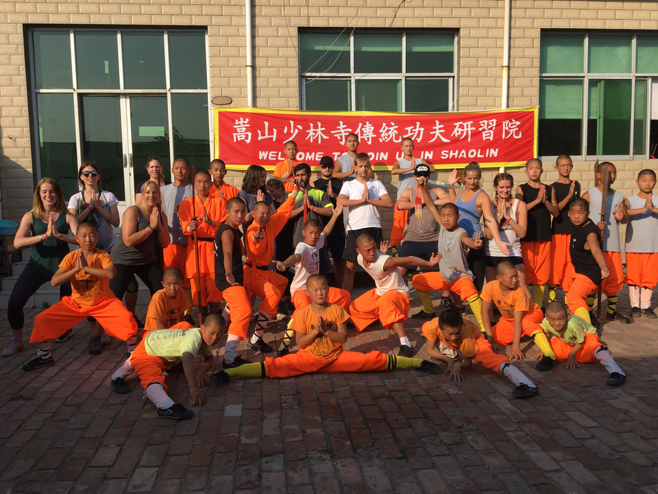 Groupe pratiquant les arts martiaux devant une bannière.