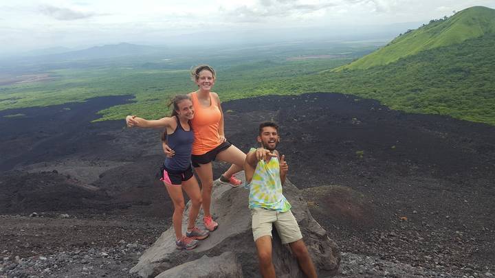 Three people posing on a hilltop with a volcanic landscape.