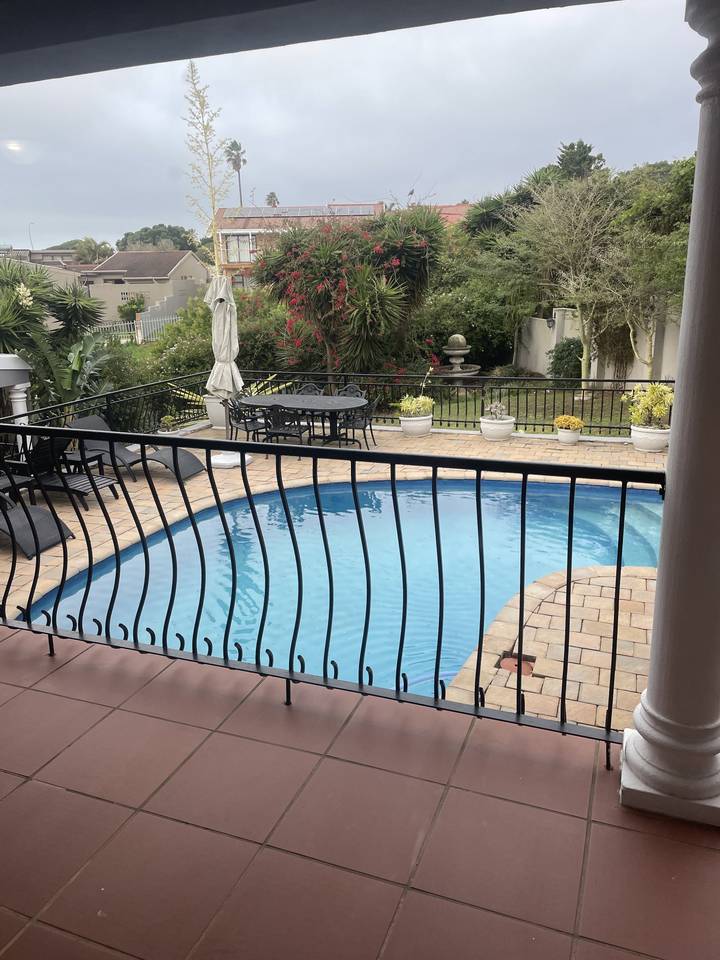 Swimming pool with surrounding plants and a balcony.