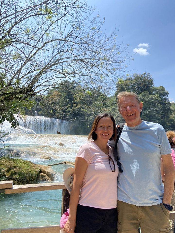 Couple de touristes posant devant une cascade.