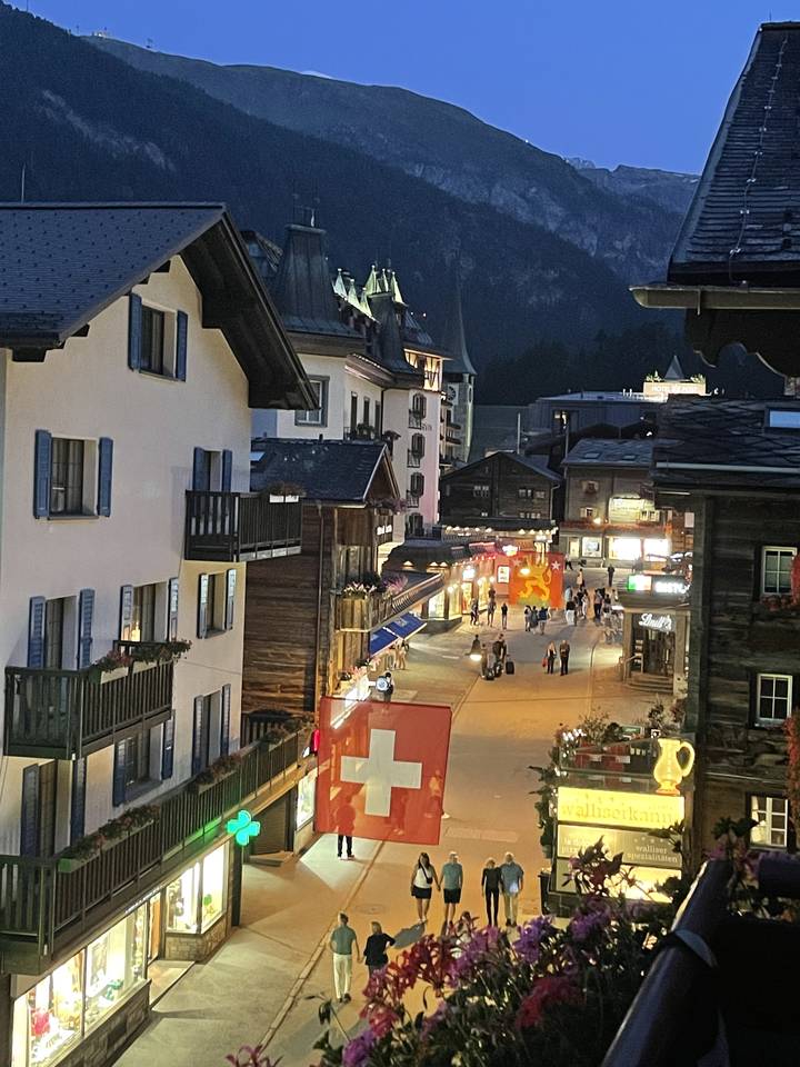 Rue avec des magasins et des drapeaux suisses le soir.