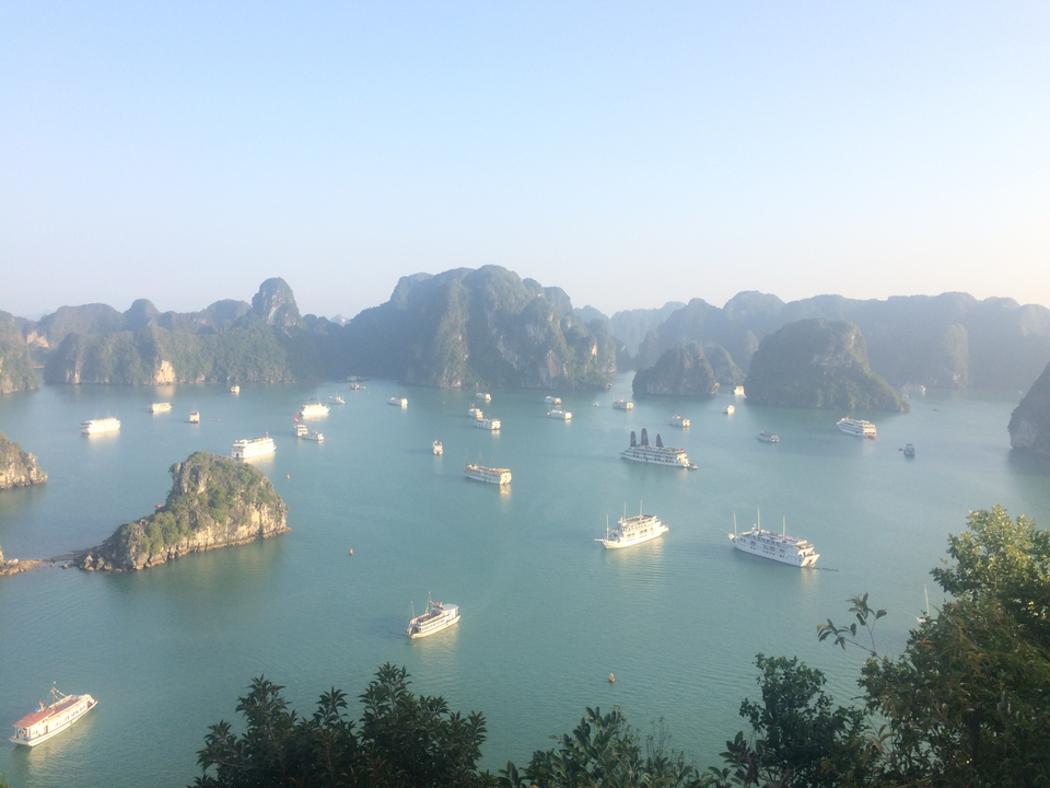 Scenic view of multiple boats sailing in a bay surrounded by limestone hills.