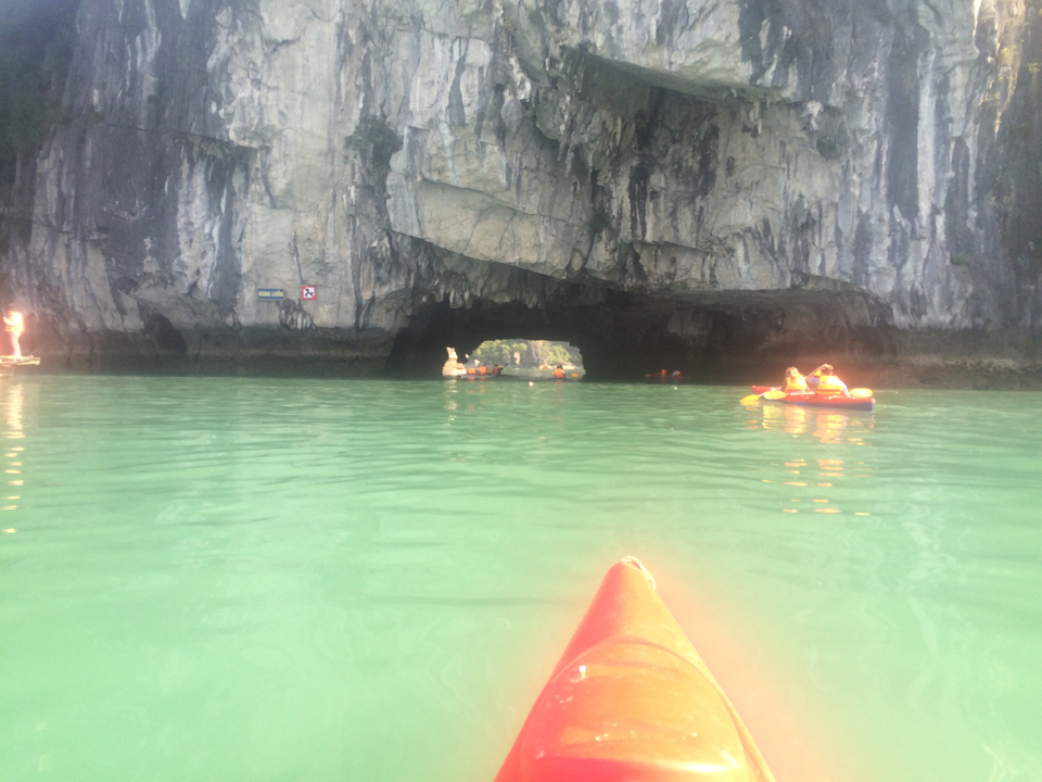 People kayaking through a cave entrance in a bay.