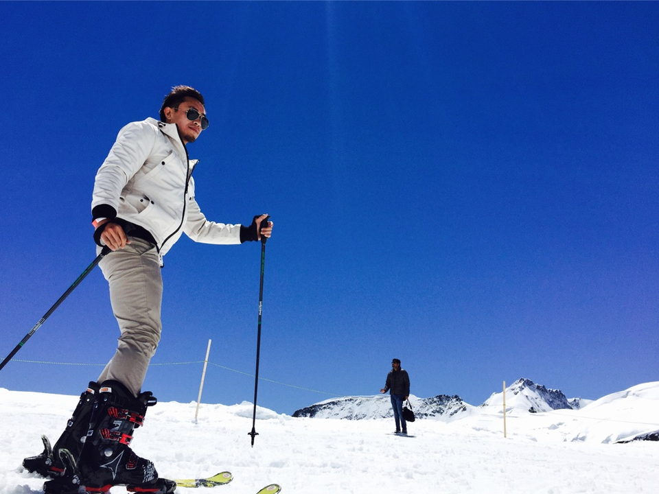 People skiing on a snowy mountain with clear blue skies.