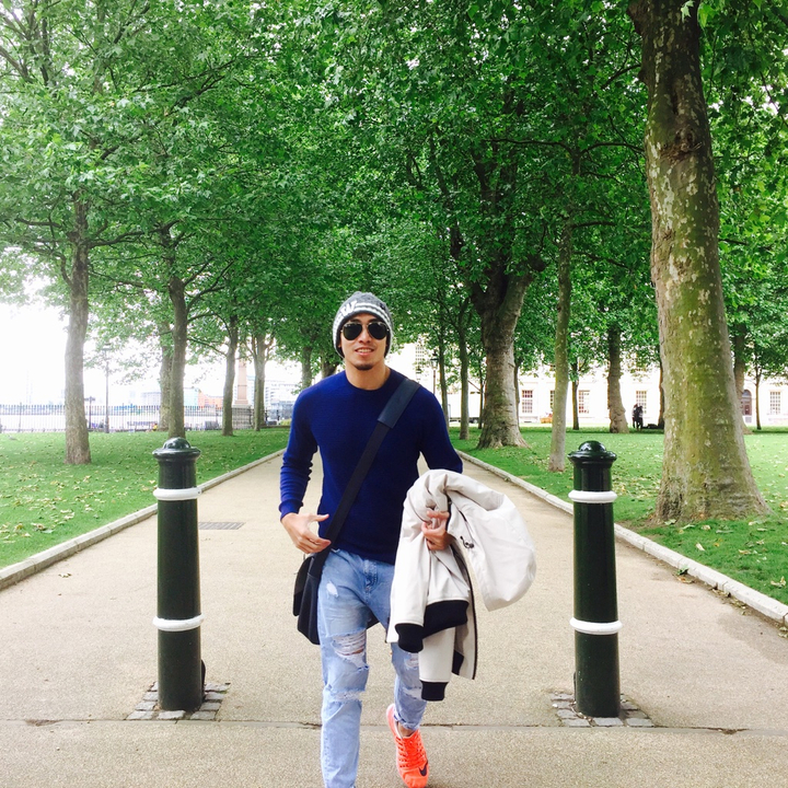 A young man walking through a tree-lined path.