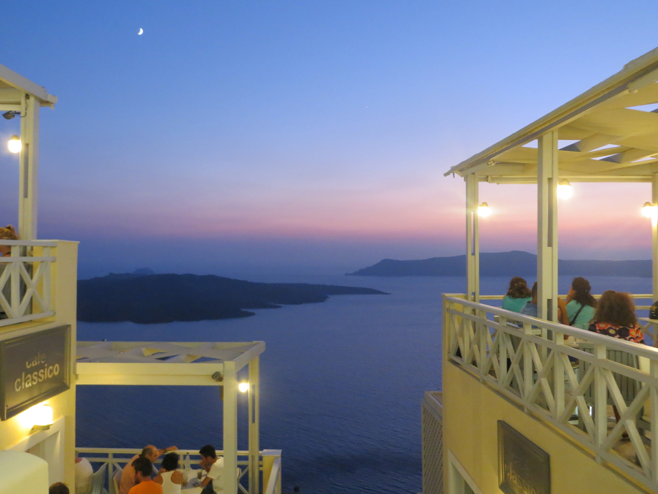 People sitting on a balcony enjoying a romantic sunset over the sea.