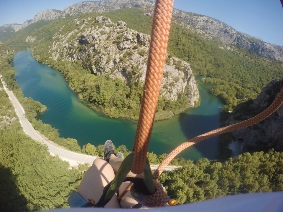 Rope and harness over a canyon and river from a zipline.