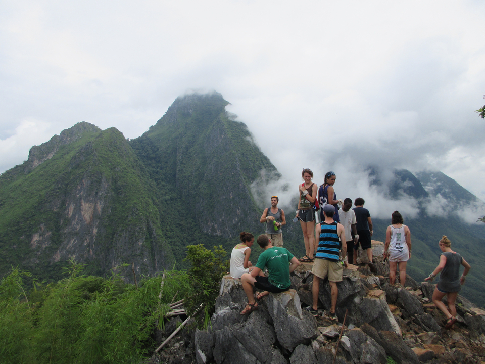 Group of people on a rocky mountain peak with misty surroundings.