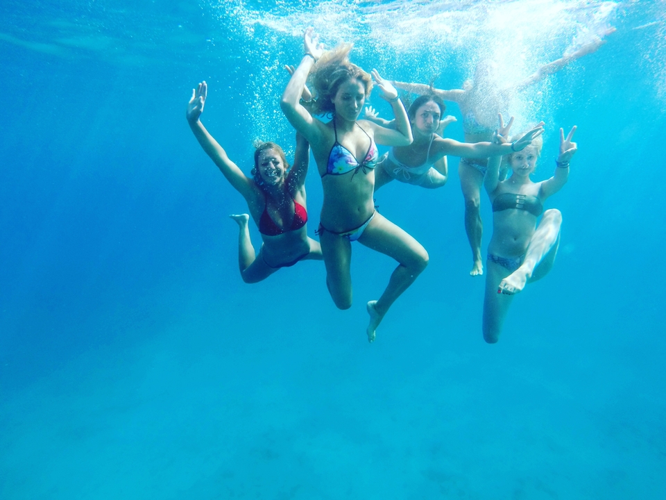 Group of people underwater swimming and posing.