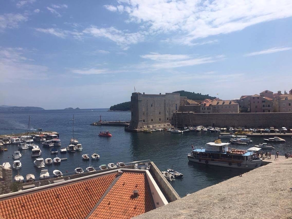 Boats and harbor within stone city walls with blue sky.