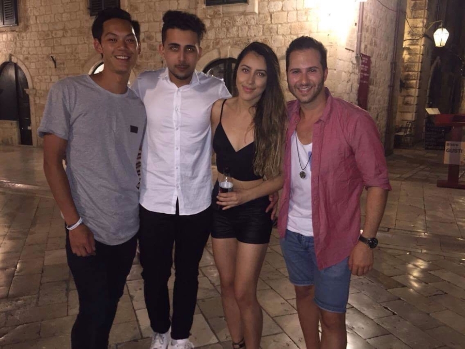 Four friends posing together on a stone-paved street at night.