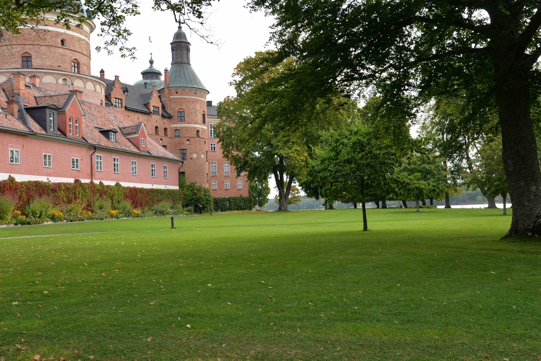 Old brick castle with green lawn and river.