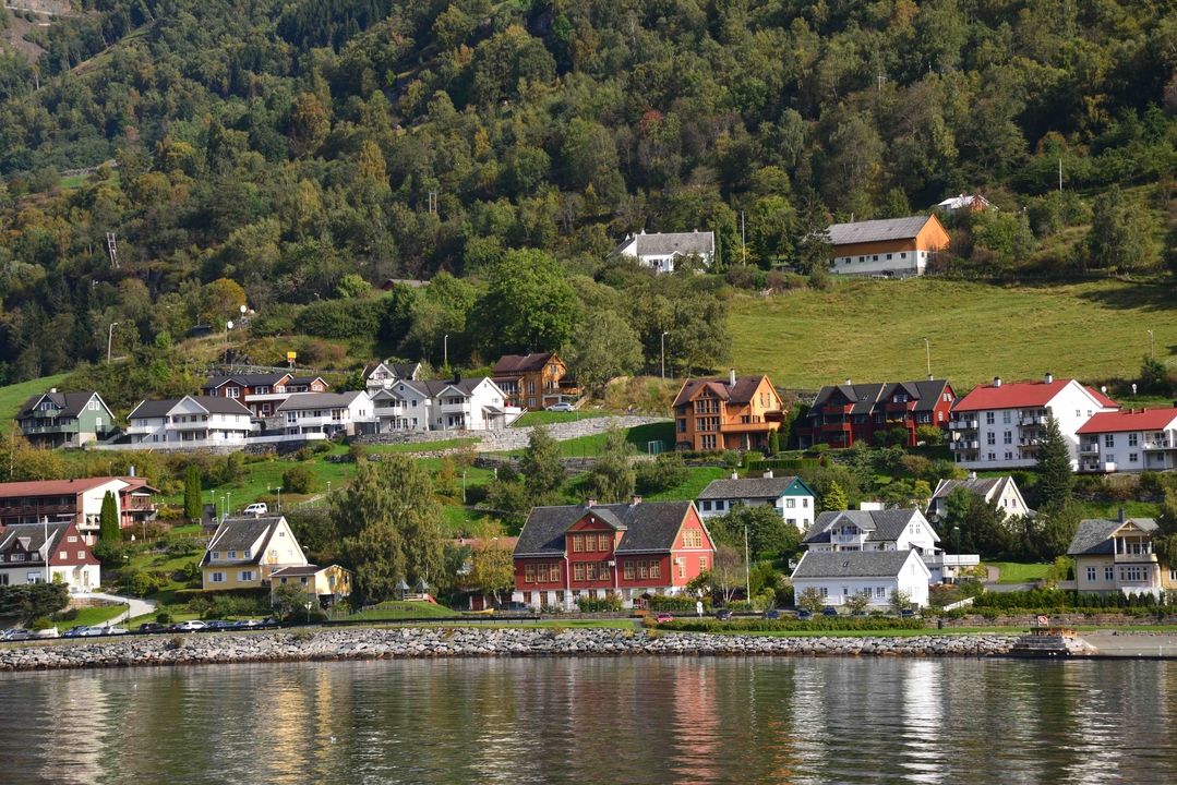 Colorful wooden houses on a slope near a river.