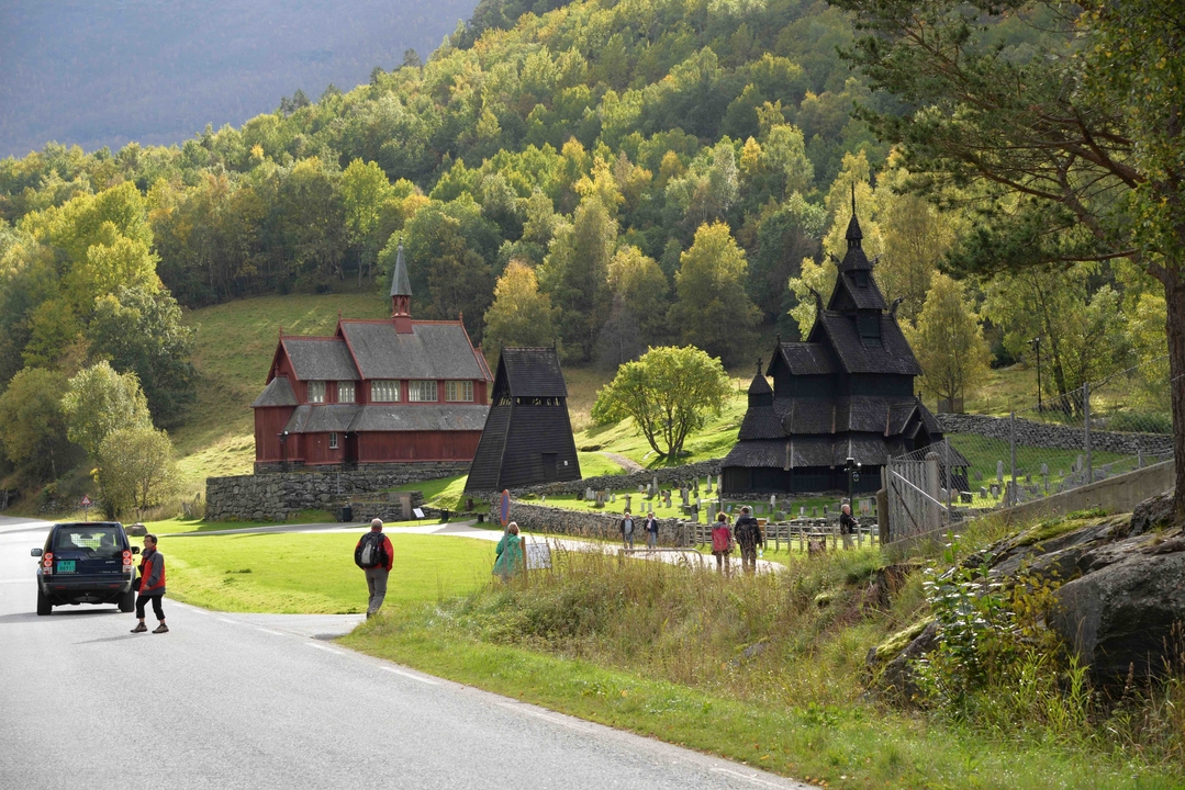 Traditional wooden church with a cemetery and tourists.
