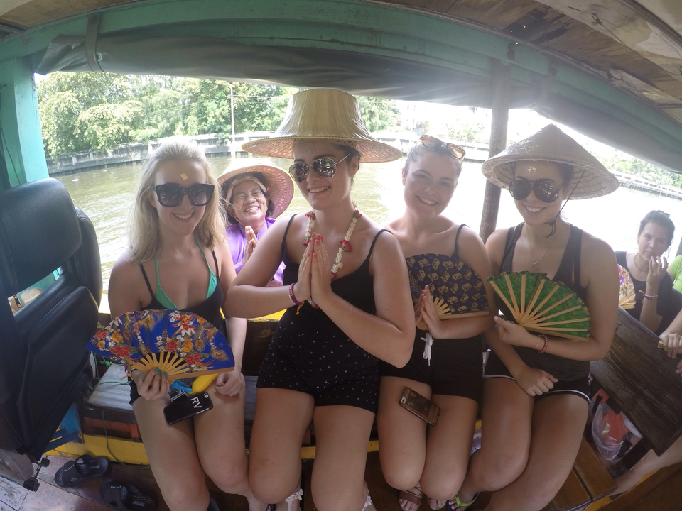 Group of women on a boat wearing traditional hats.