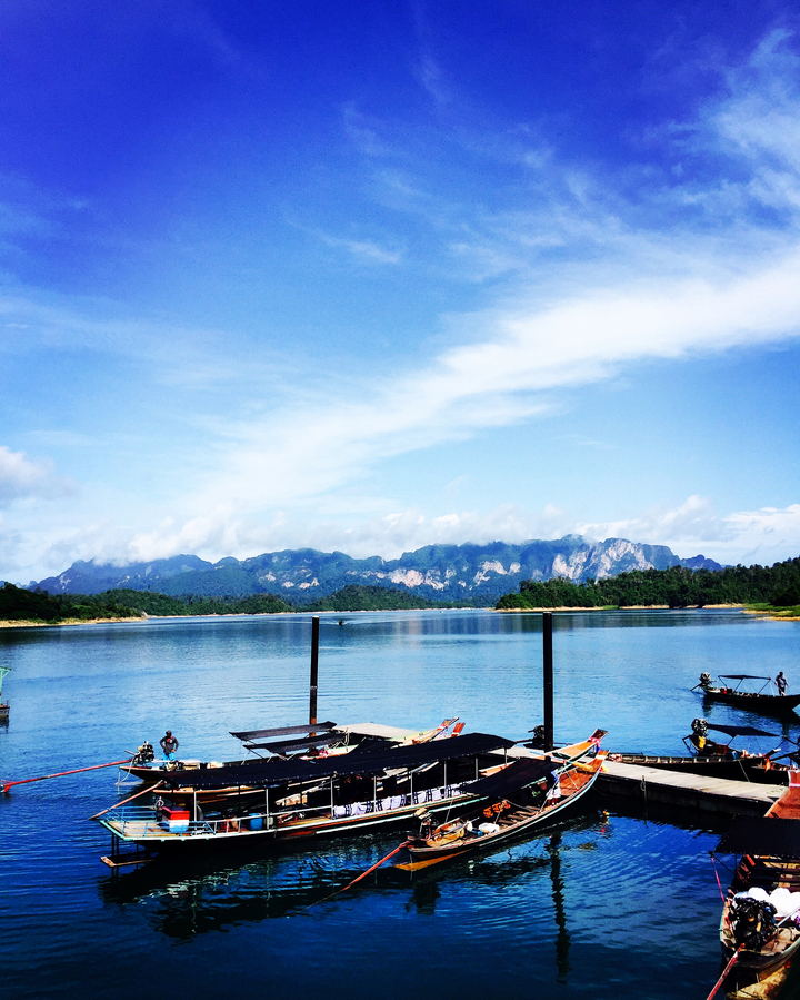 Scenic view of mountains reflected in a large lake under a blue sky.