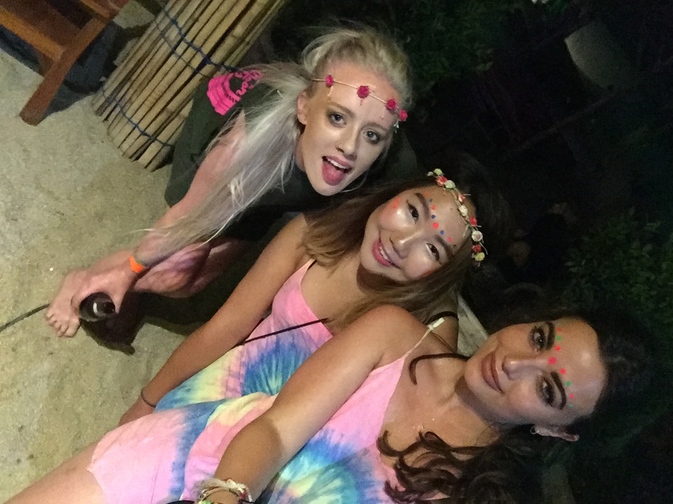 Three young women wearing colorful makeup and clothes at a party.