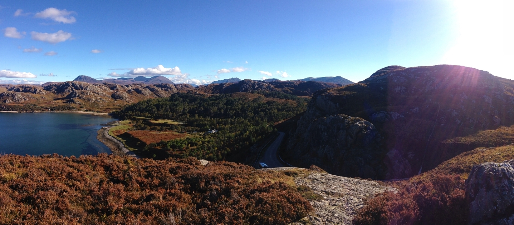 Expansive view of rugged mountains and road in Scotland.